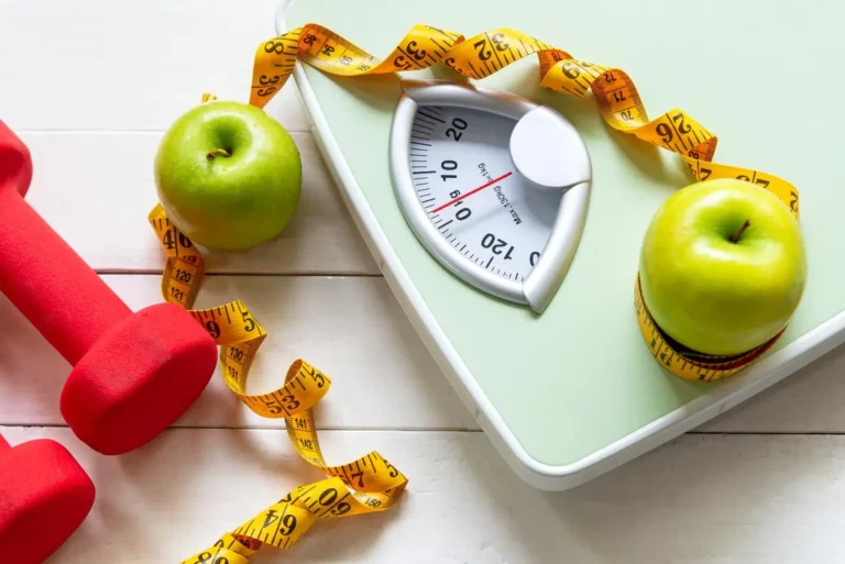 Báscula con cinta métrica, manzanas y pesas para control de peso y alimentación saludable